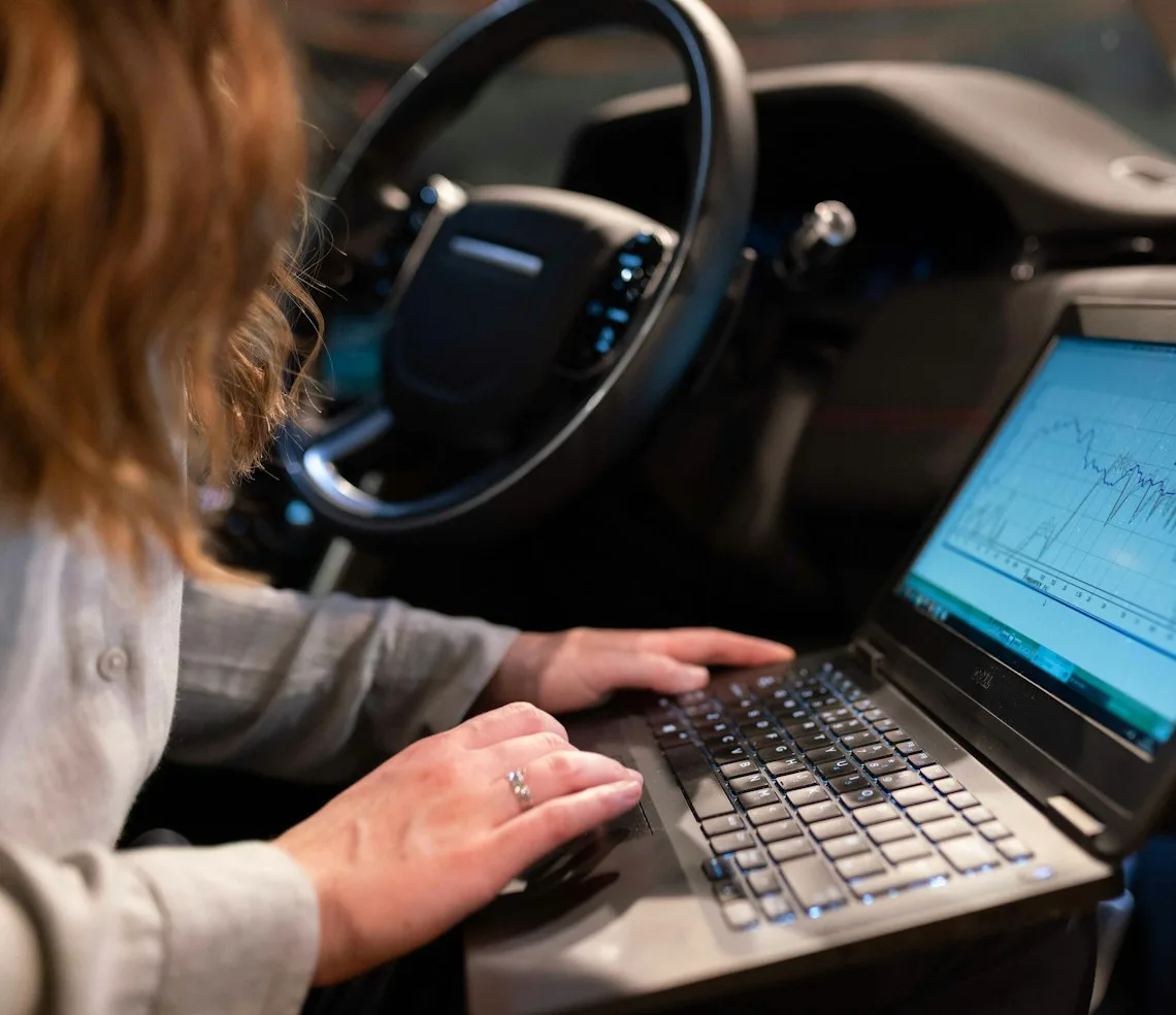 An auto electrician running diagnostics from a laptop in the car