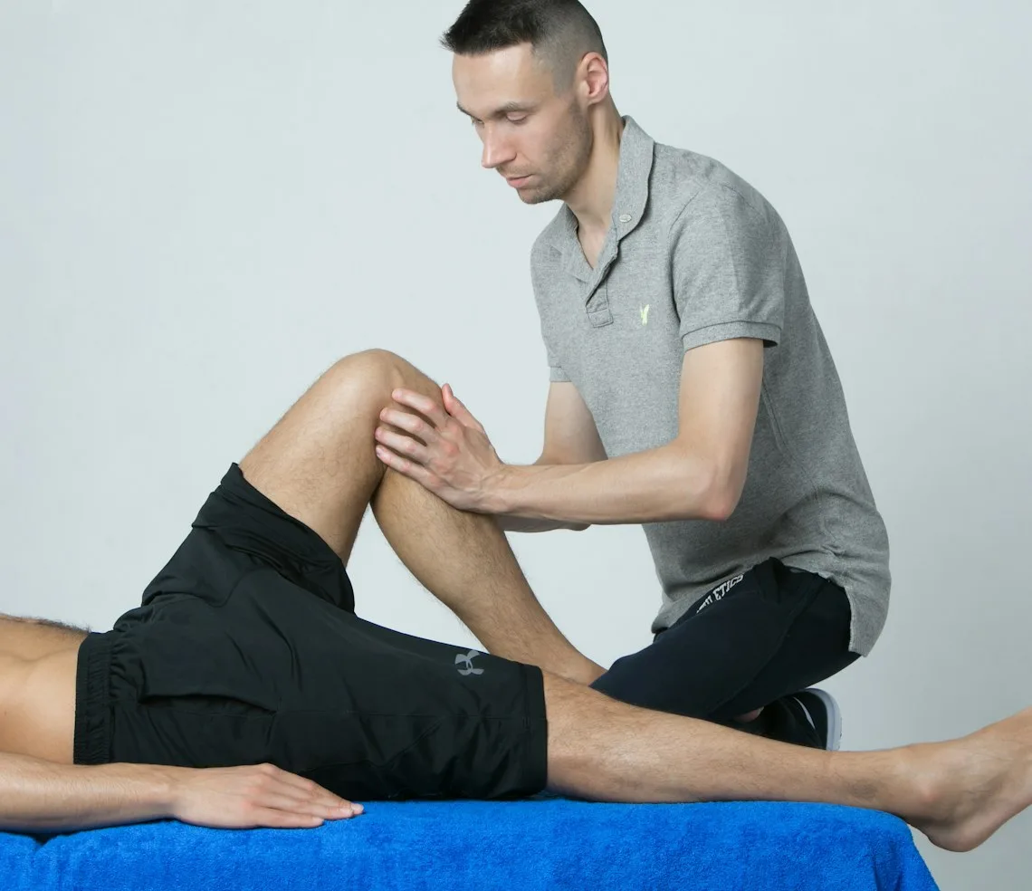 A physiotherapist working on a patient’s knee on the couch