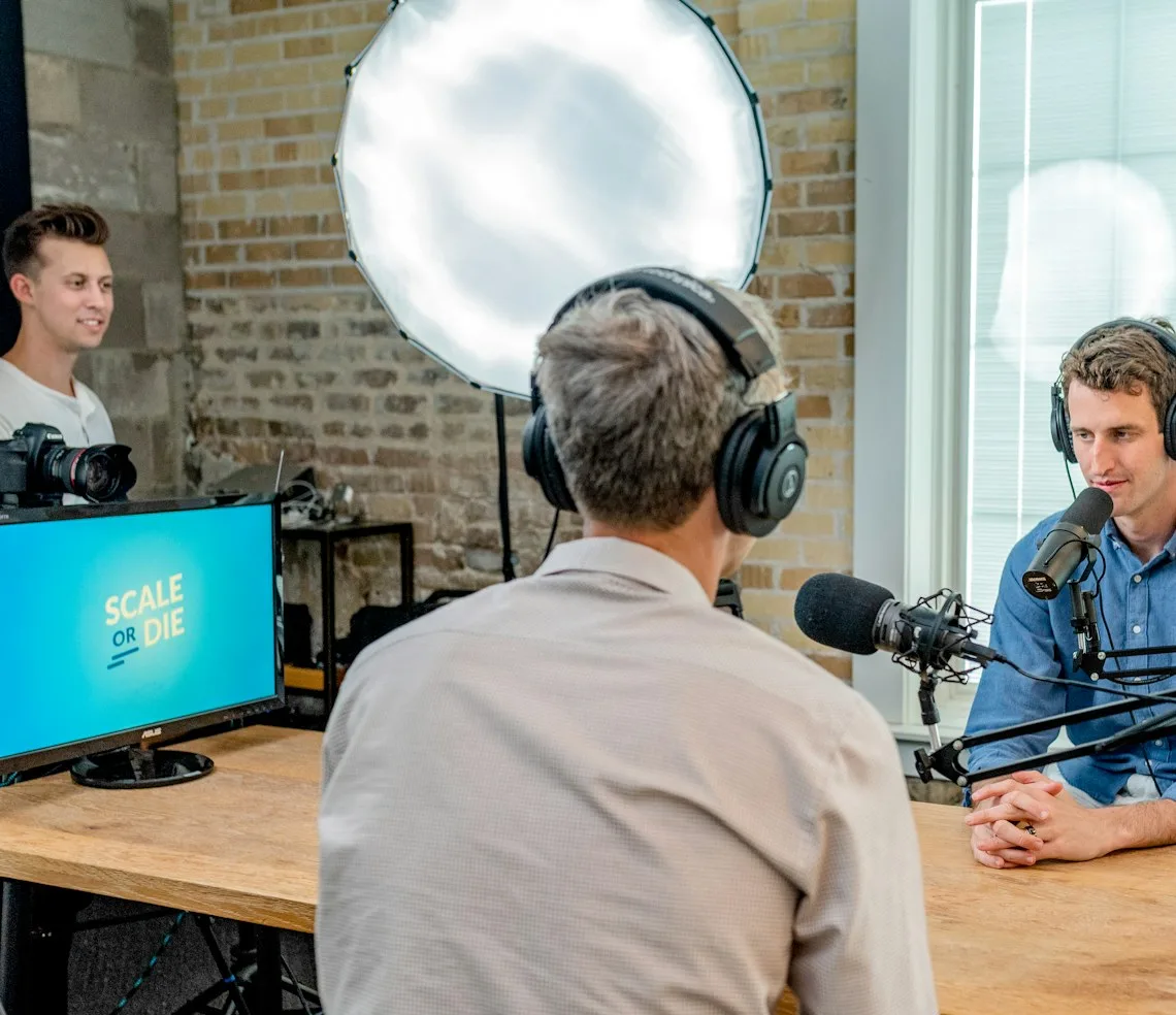 A host and a guest recording an episode at studio microphones
