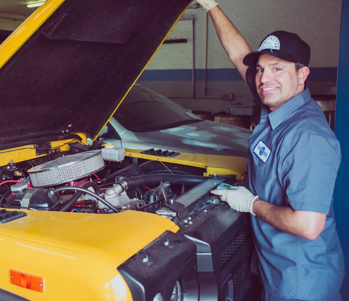 A mechanic looking over an engine under an open bonnet