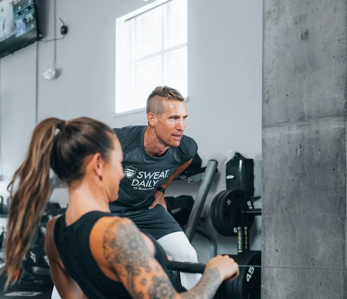 A trainer helping a client through a set on a machine in the gym