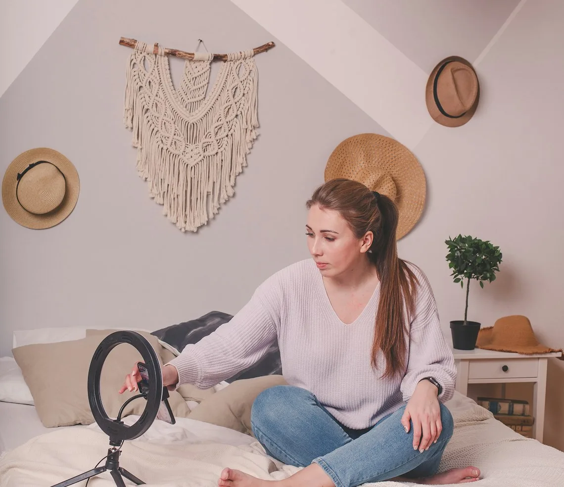 A creator filming a video on a phone mounted on a tripod under a ring light