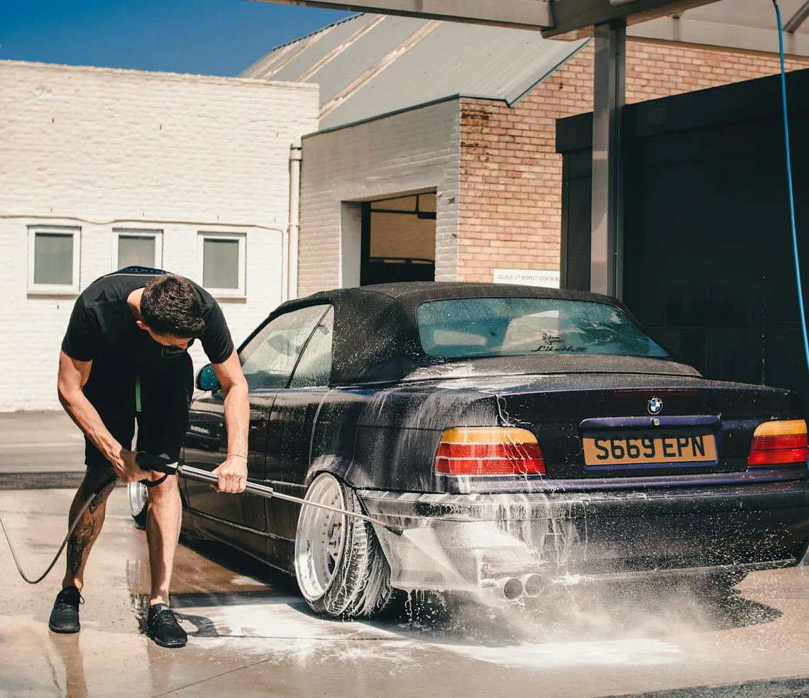 A washer cleaning a car with a pressure washer