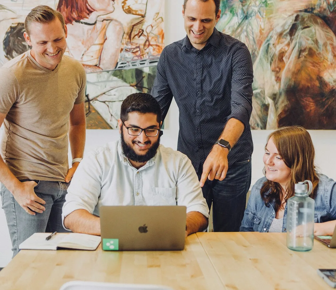 A development team working around a laptop in the office