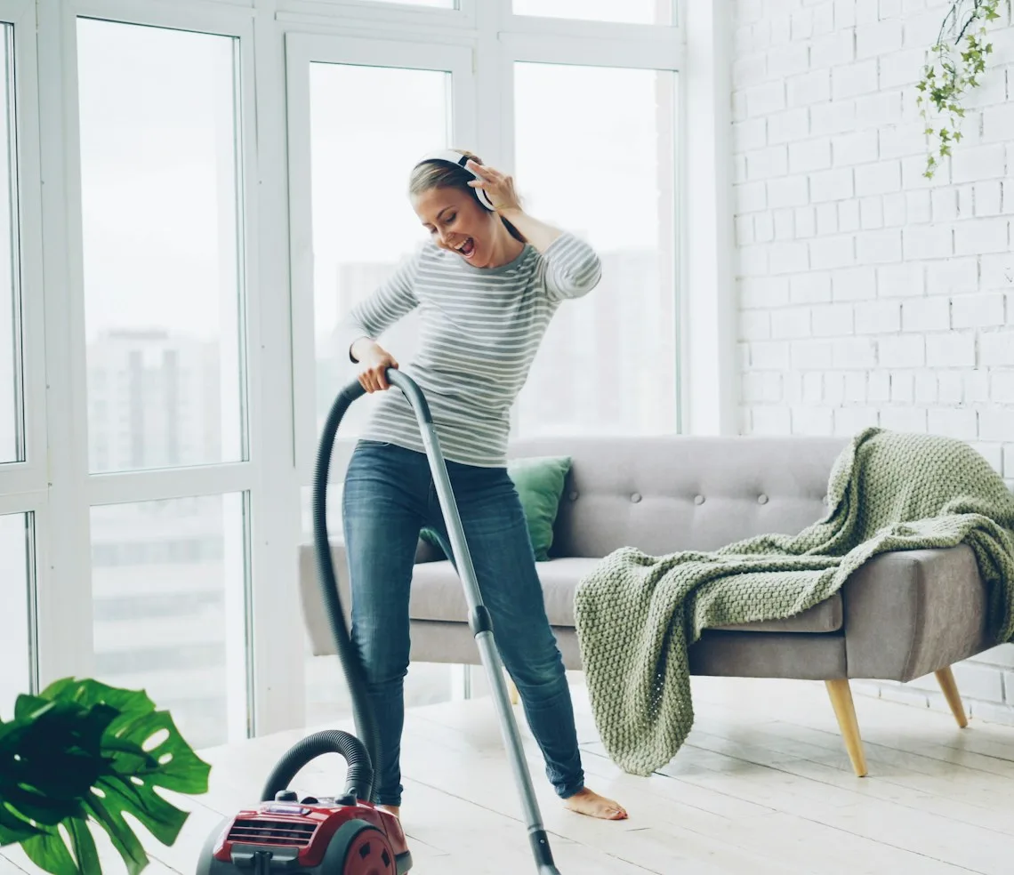 A cleaner vacuuming the living room of a bright flat