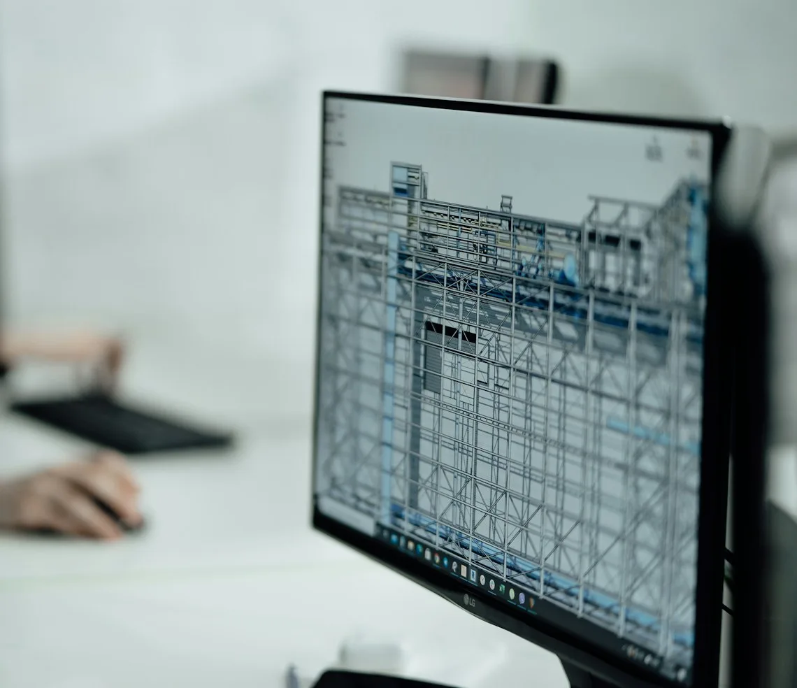An architect working on a 3D model of a building on screen