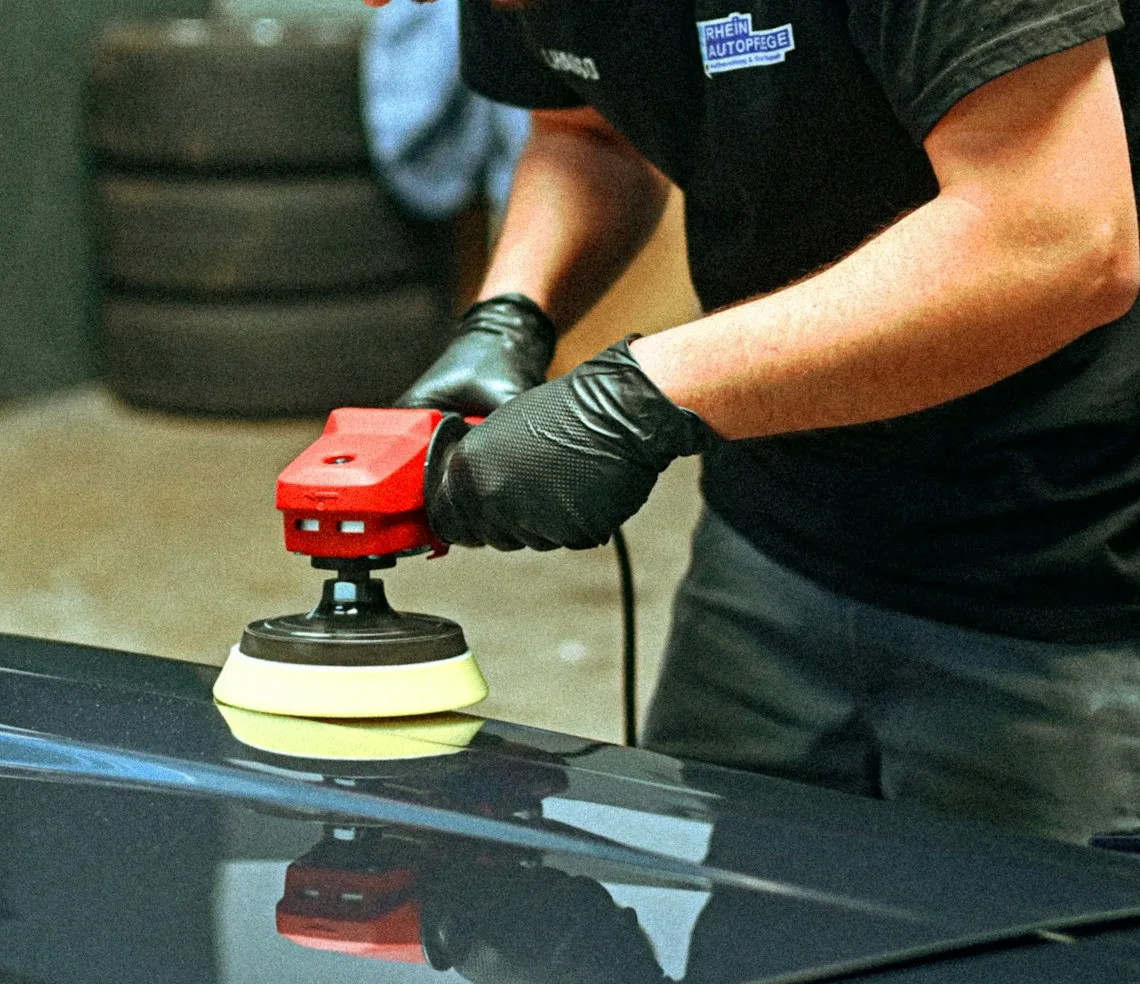 A detailer polishing a body panel with a machine in the bay