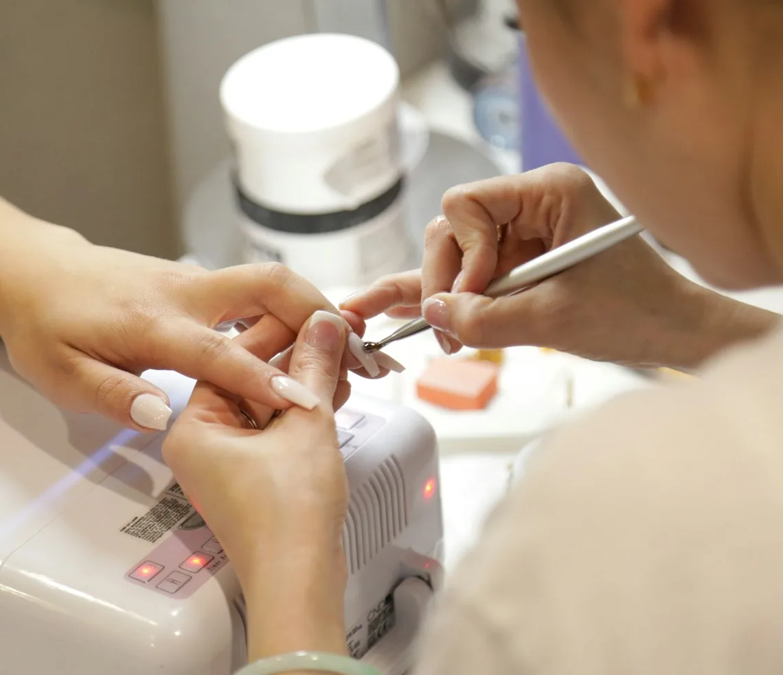 A technician working on a client’s manicure at the desk