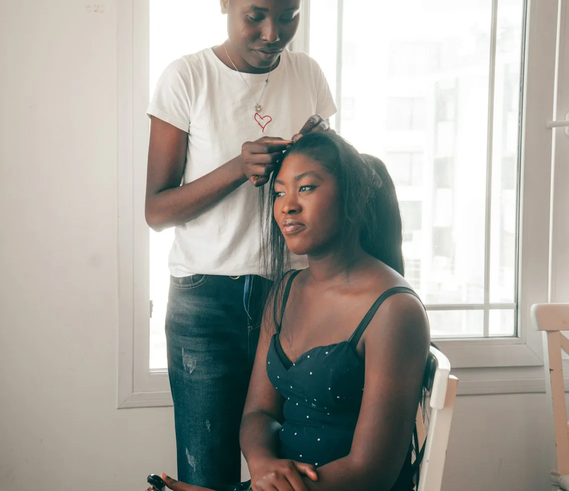 A stylist working on a client’s hair by the window in the salon