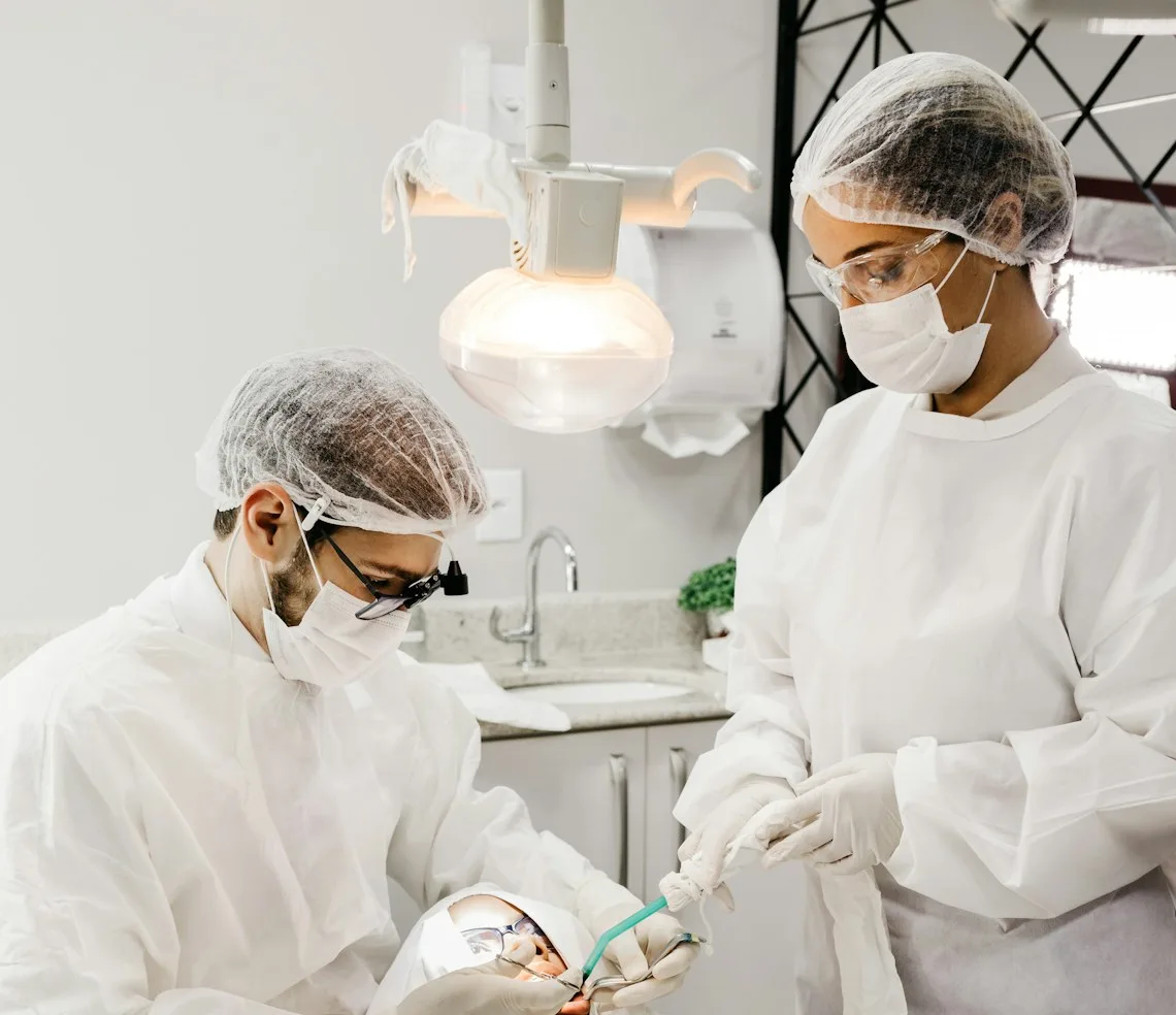 A dentist and an assistant working with a patient in the chair