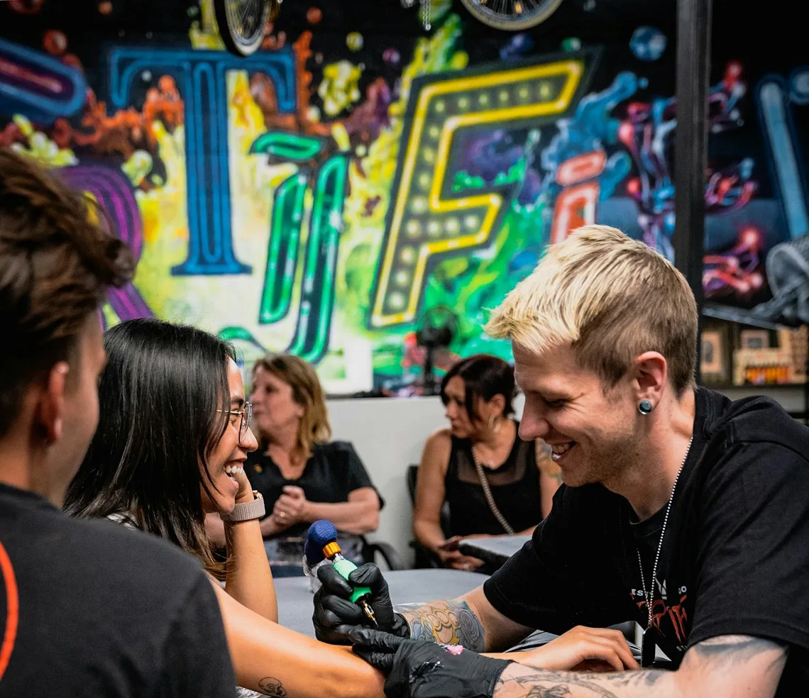 A tattoo artist working on a piece on a client’s arm in the studio