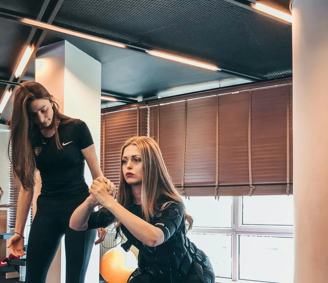 A personal trainer showing a client the technique for a weighted exercise